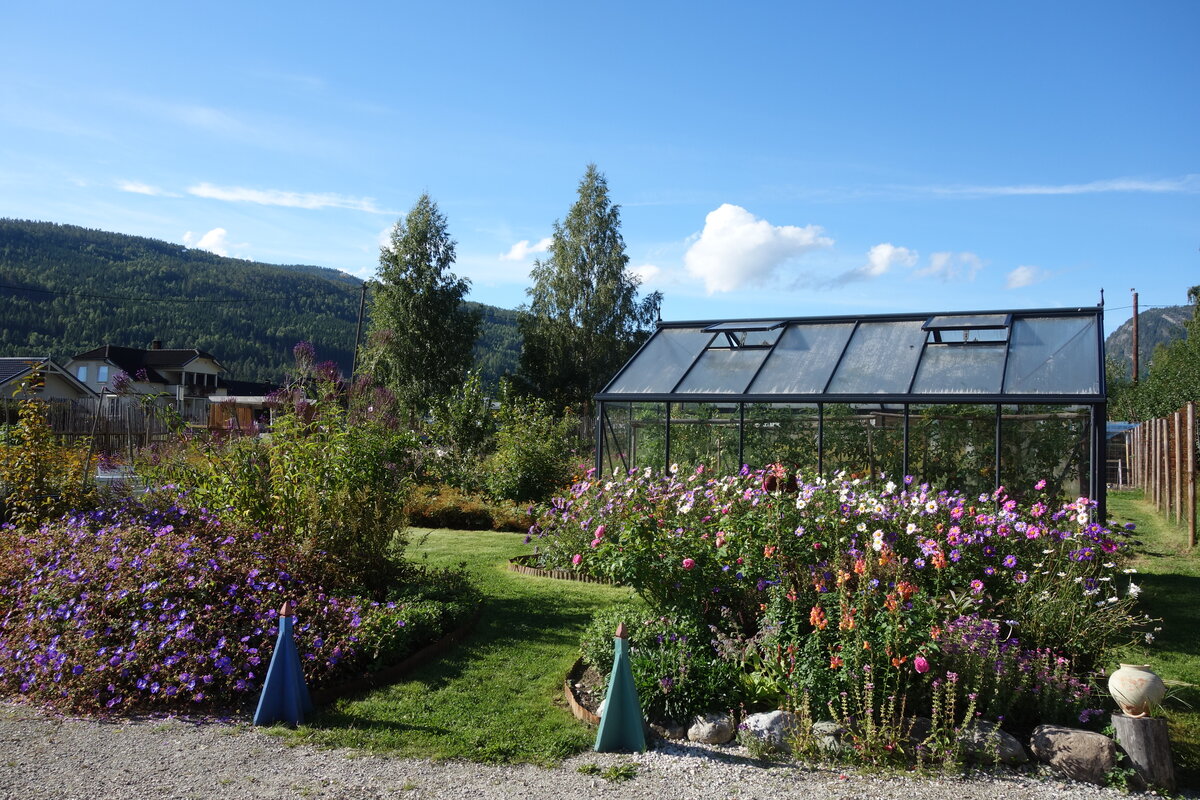 Blomsterbed og drivhus med fjell i bakgrunnen